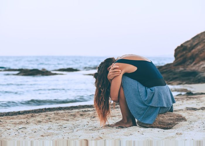 woman battling summer depression on the beach.