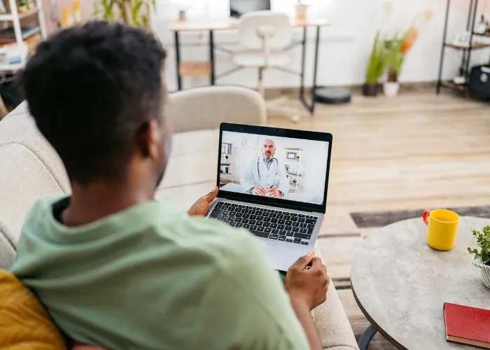 adult man sitting on a couch during a telehealth appointment.