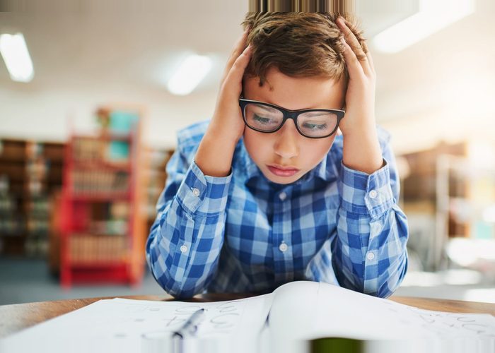 Shot of a young boy looking stressed out while working in class at school
