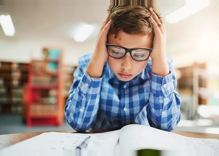 Shot of a young boy looking stressed out while working in class at school