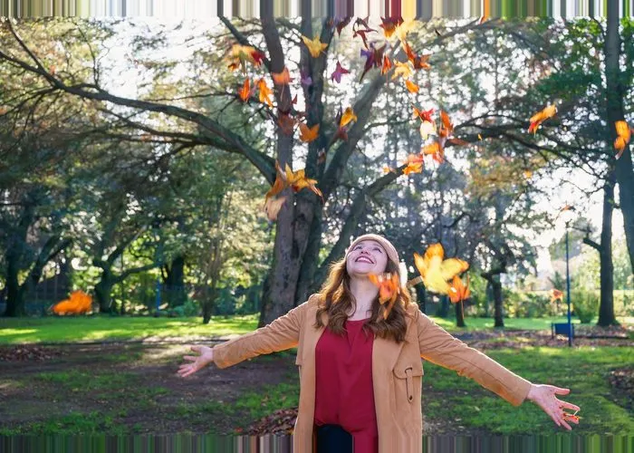 Young latin woman enjoying autumn leaves in a park