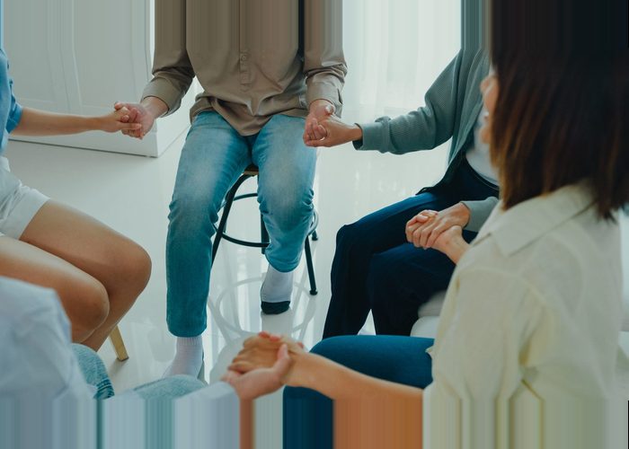 Close-up of a group of psychotherapists holding hands during talking about mental health problems. People use group therapy to support each other in recovering from the sadness concept.