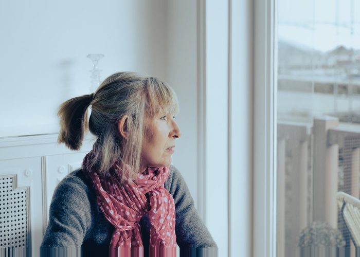 Lonely mature woman looking blankly out of the window.