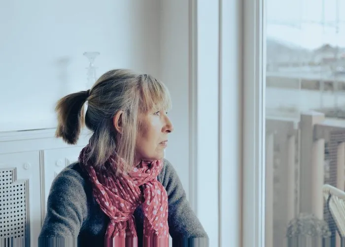Lonely mature woman looking blankly out of the window.
