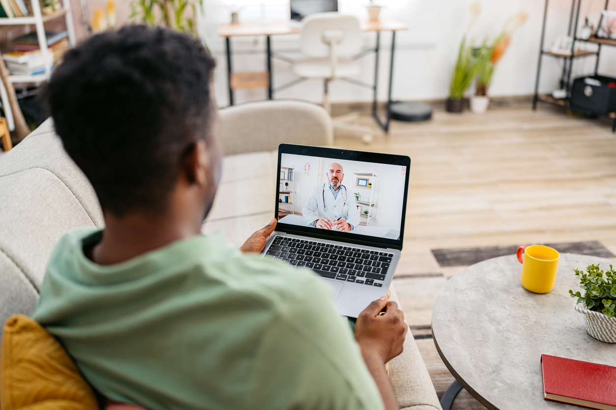 adult man sitting on a couch during a telehealth appointment.